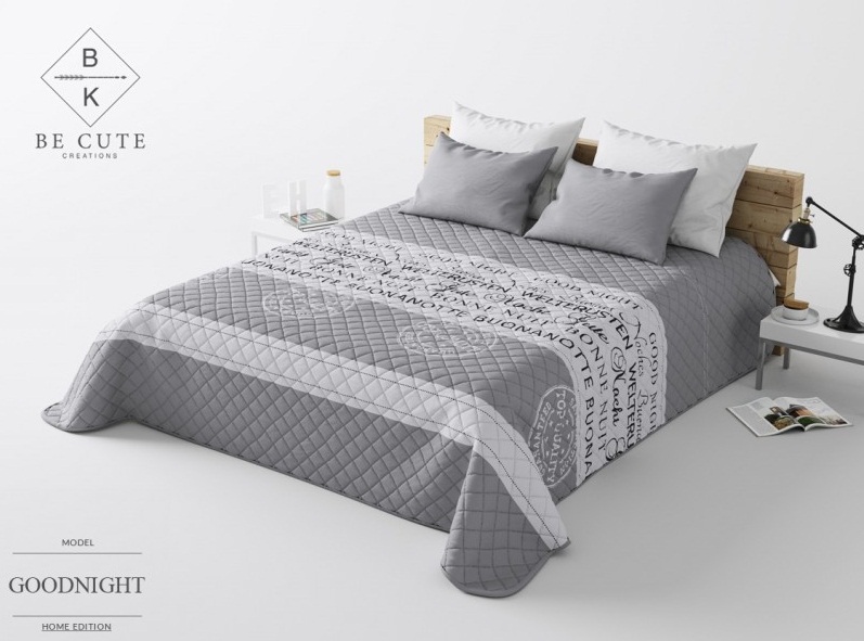 Szara narzuta pikowana na łóżko w białe napisy