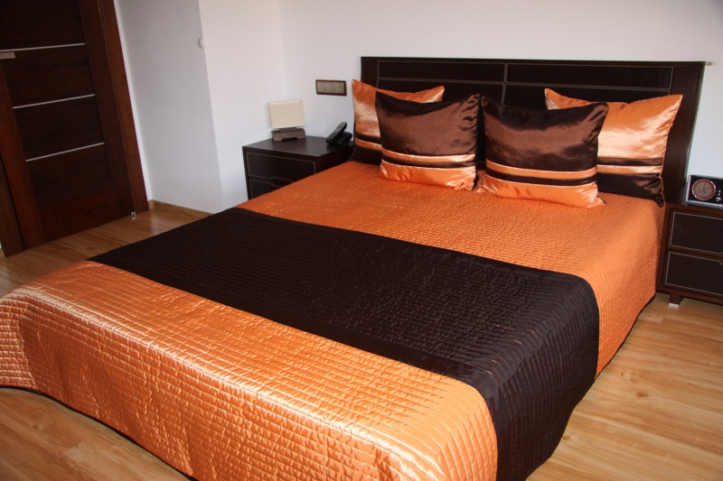Narzuta na małe i duże łóżka w kolorze pomarańczowym z czekoladowym pasem